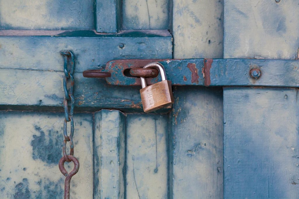 pexels photo 164425 164425 A close-up of a rusty padlock securing a blue painted wooden door with chain and bolt.